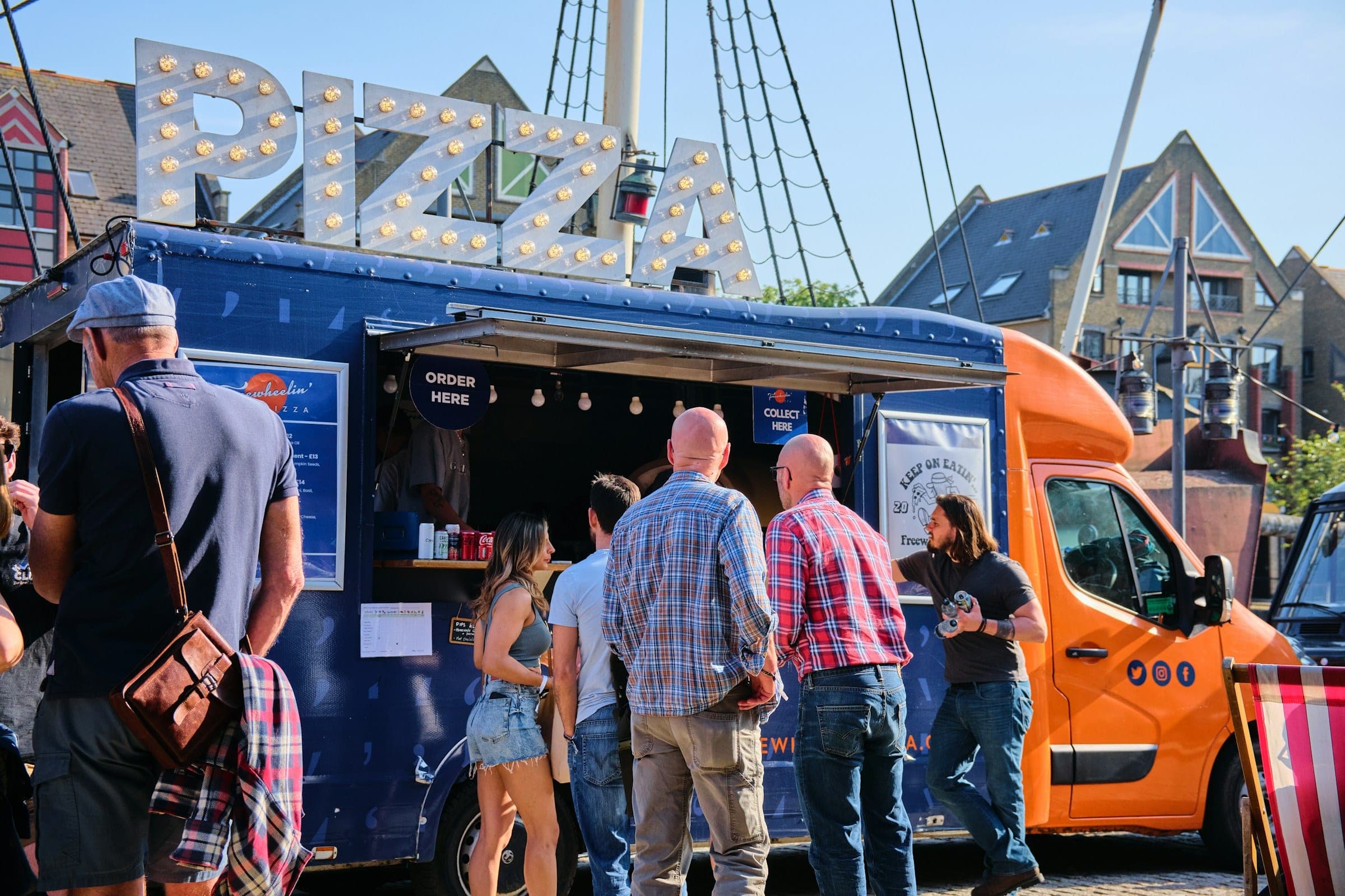 Customers lining up to order at a mobile food truck parked on a private lot